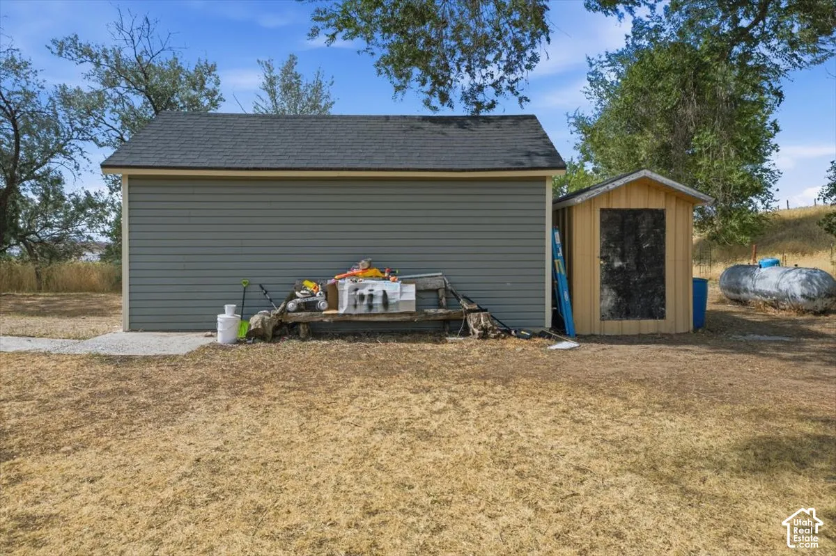 Detached outbuilding with gray horizontal siding and a dark shingle roof