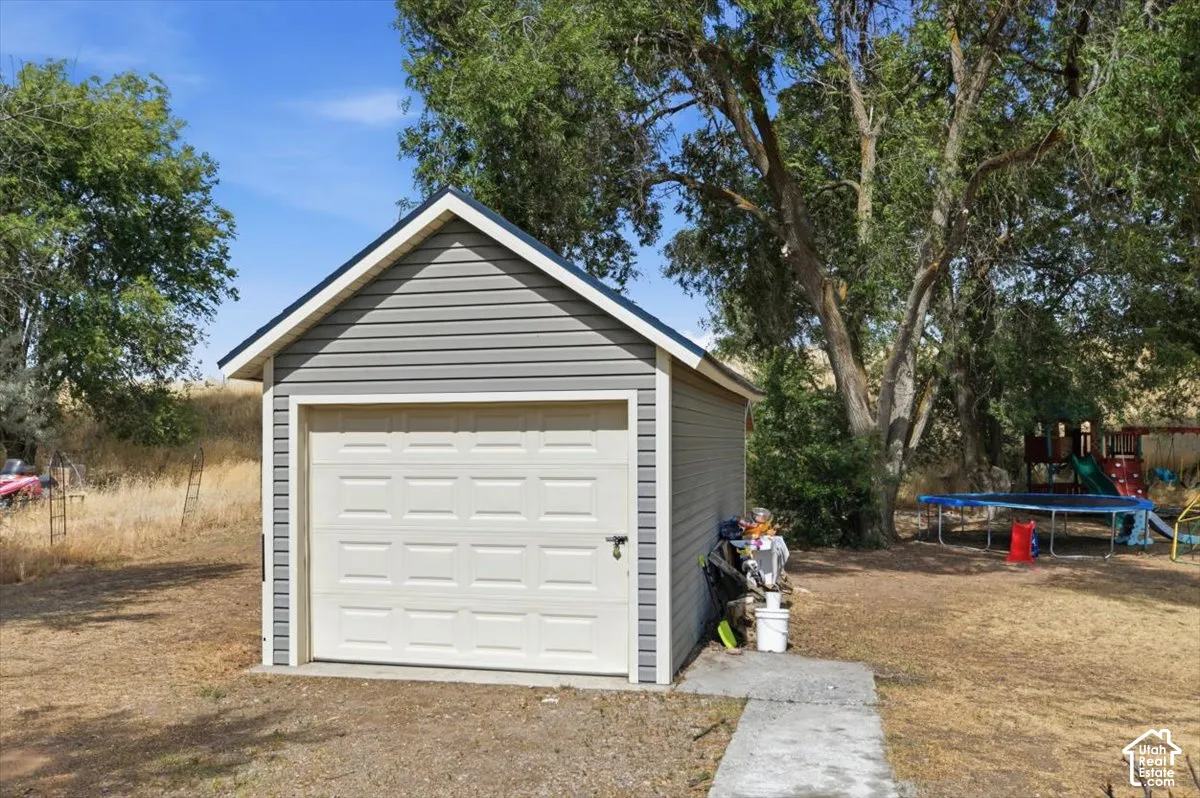 Detached garage with gray siding and a paneled overhead door, featuring a concrete pad and a pitched roof