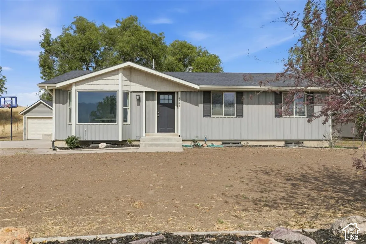Ranch-style residence featuring vertical siding, a deep gray entry door, and a detached garage