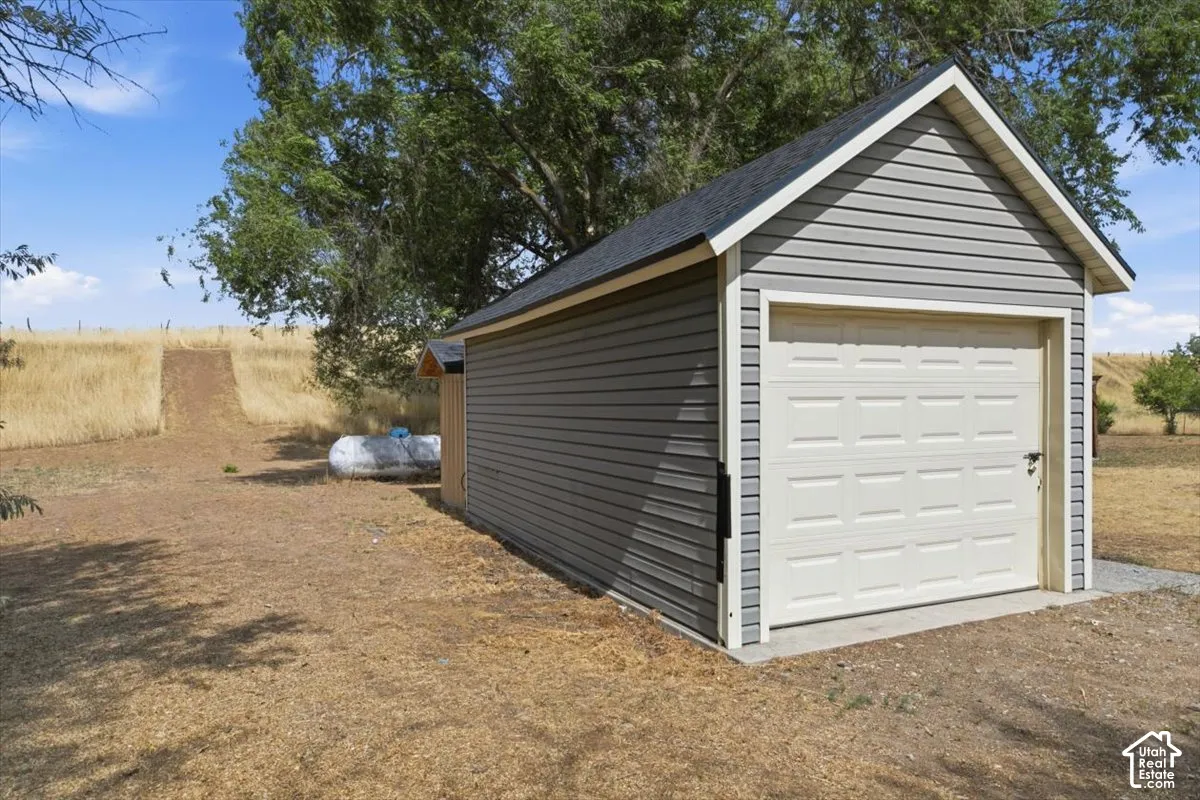 Detached garage featuring gray horizontal siding, white trim, and a white paneled garage door