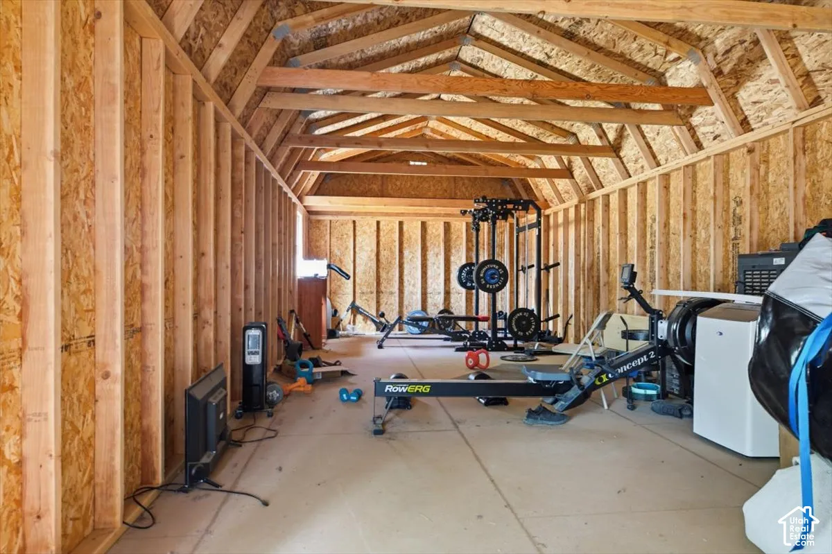 Spacious unfinished attic space featuring exposed wood framing and particle board walls