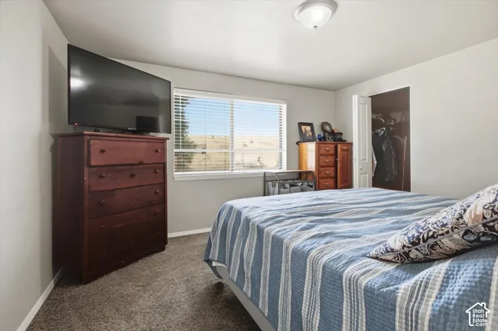 Carpeted bedroom featuring a window with horizontal blinds, providing natural illumination