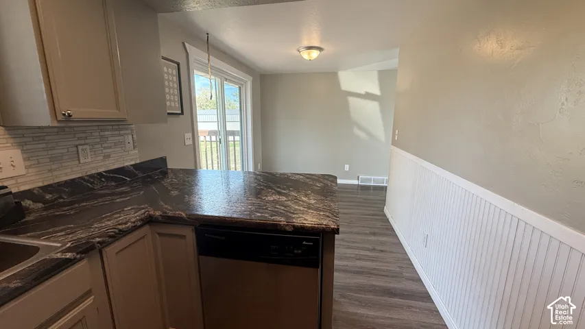 Kitchen featuring dark patterned countertops, light-colored cabinetry, a tile backsplash, and integrated dishwasher