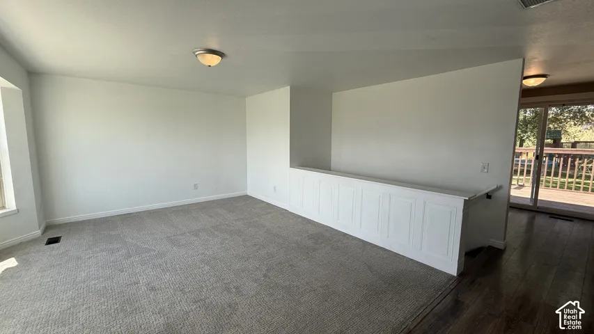 Carpeted flooring, white paneled half-wall, sliding glass door, wood-finish flooring, and flush mount lighting