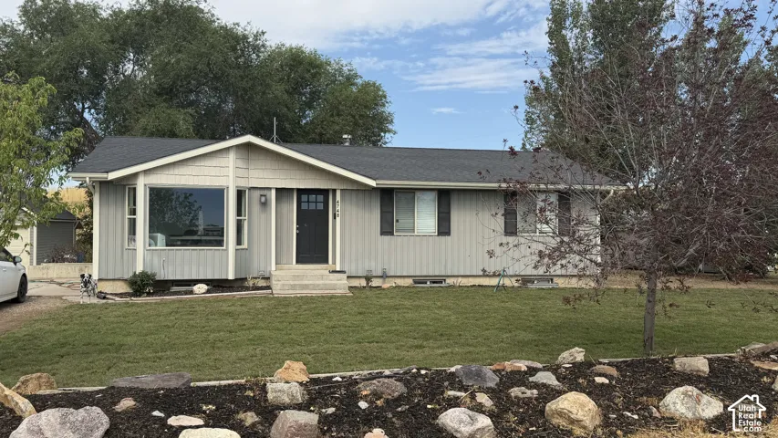 Ranch-style residence featuring light gray vertical siding, a dark gray shingle roof, and a prominent bay window