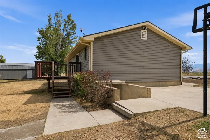 Gray siding exterior with a wood deck, concrete patio, and a concrete pathway leading to the deck