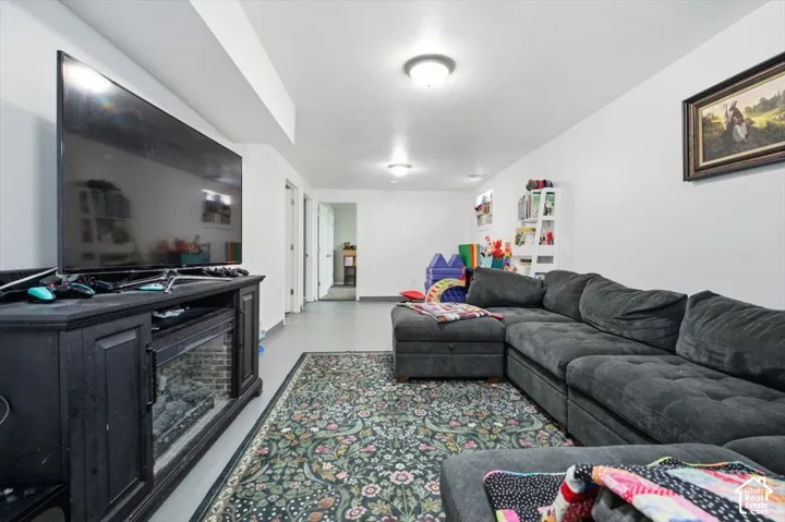 Spacious lower-level room featuring light gray flooring and multiple overhead light fixtures
