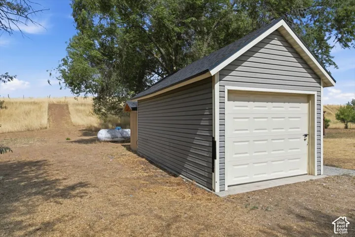 Detached garage featuring gray horizontal siding, white trim, and a white paneled garage door
