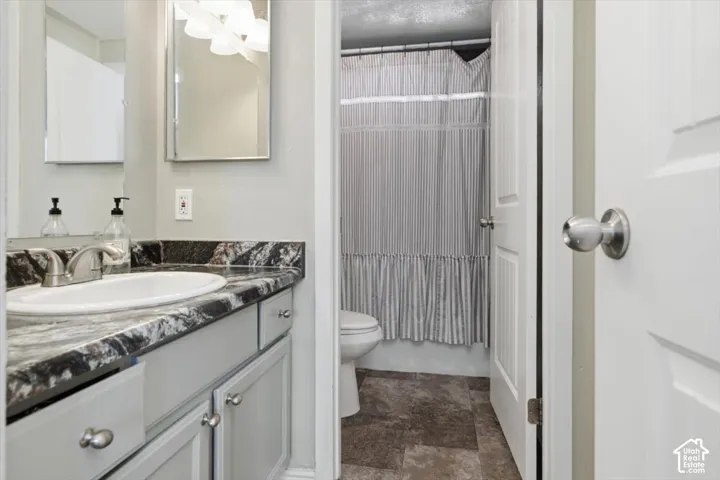 Bathroom vanity featuring a single basin, dark veined countertop, light gray cabinetry, and brushed nickel hardware