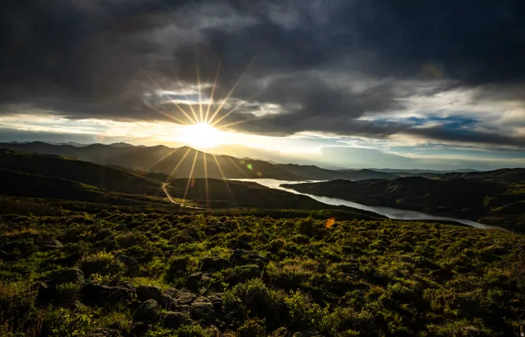 Expansive natural landscape featuring rolling hills and a prominent body of water