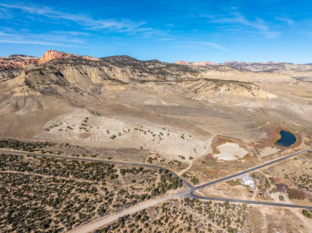 Expansive desert landscape featuring distant mountains, two ponds, and a single-family residence