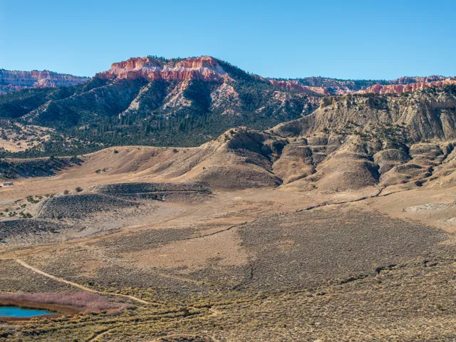 Expansive desert landscape featuring rolling hills and distant red rock formations