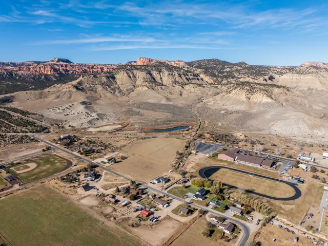 Expansive rural landscape featuring a cluster of residential structures, open fields, and a distant mountainous backdrop