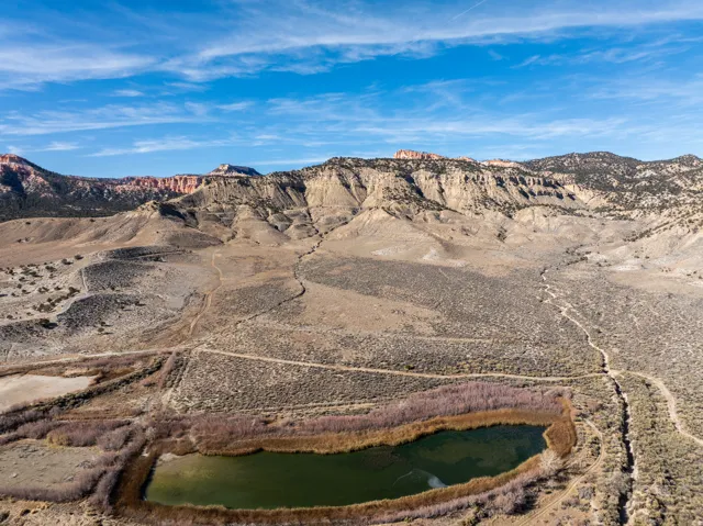 Aerial landscape featuring varied terrain, a body of water, and distant mountain ranges