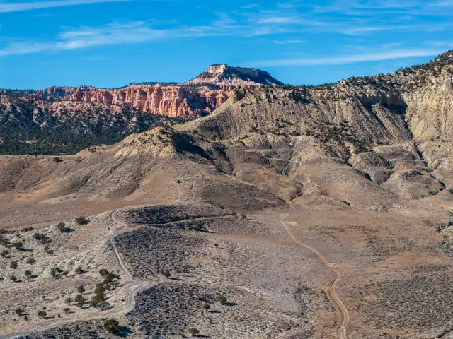 Expansive desert landscape featuring rugged terrain and distant red rock formations