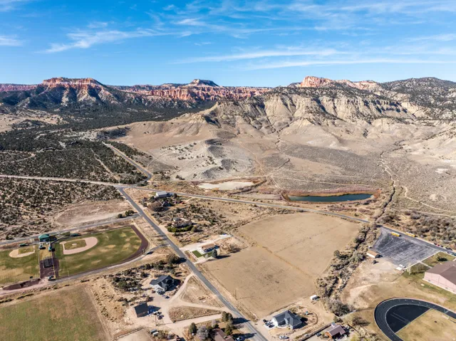 Expansive land parcel with surrounding mountain vistas, a visible pond, and direct road frontage