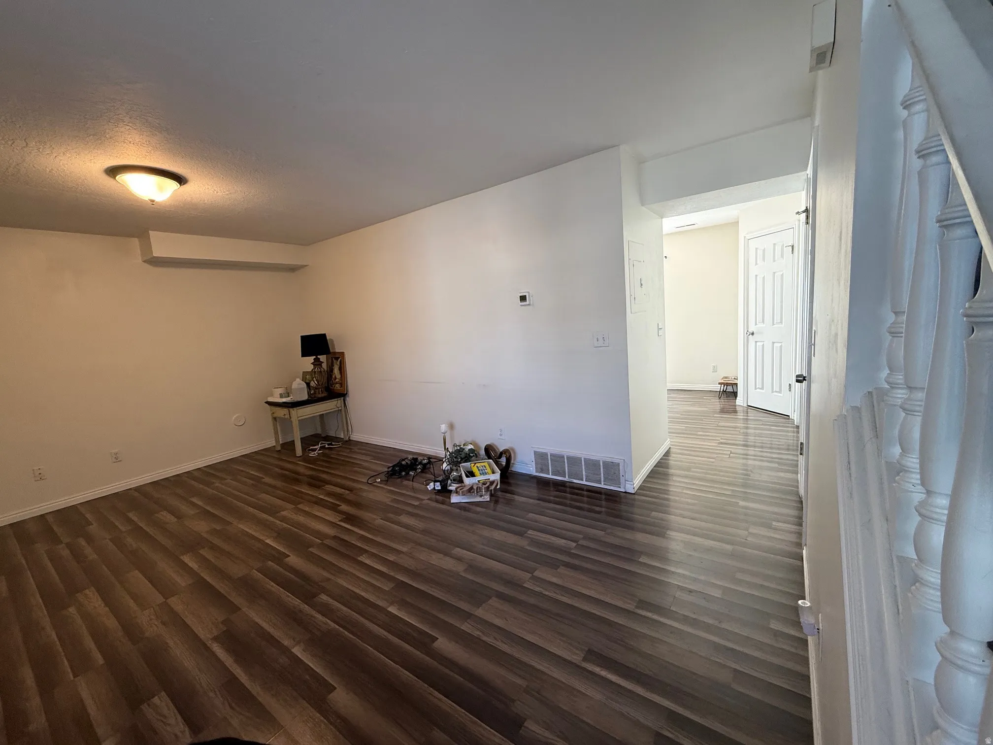Spacious room with wood-finish flooring, white baseboards, and neutral wall tones