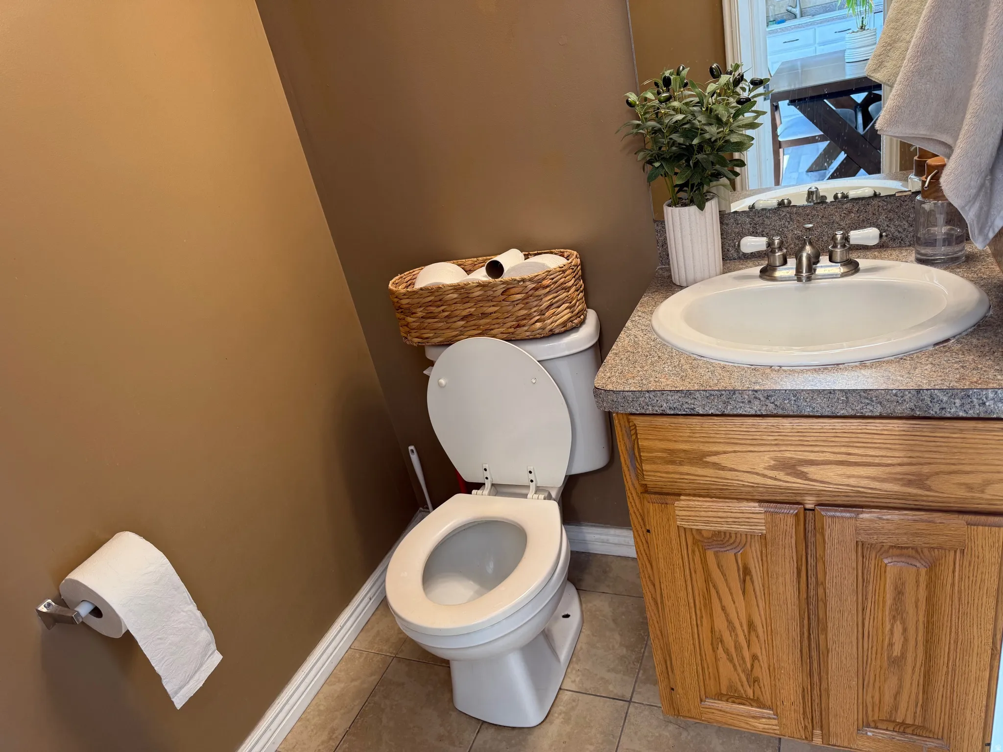 Bathroom featuring a single vanity with wood-finish cabinetry, a speckled countertop, and a white porcelain sink