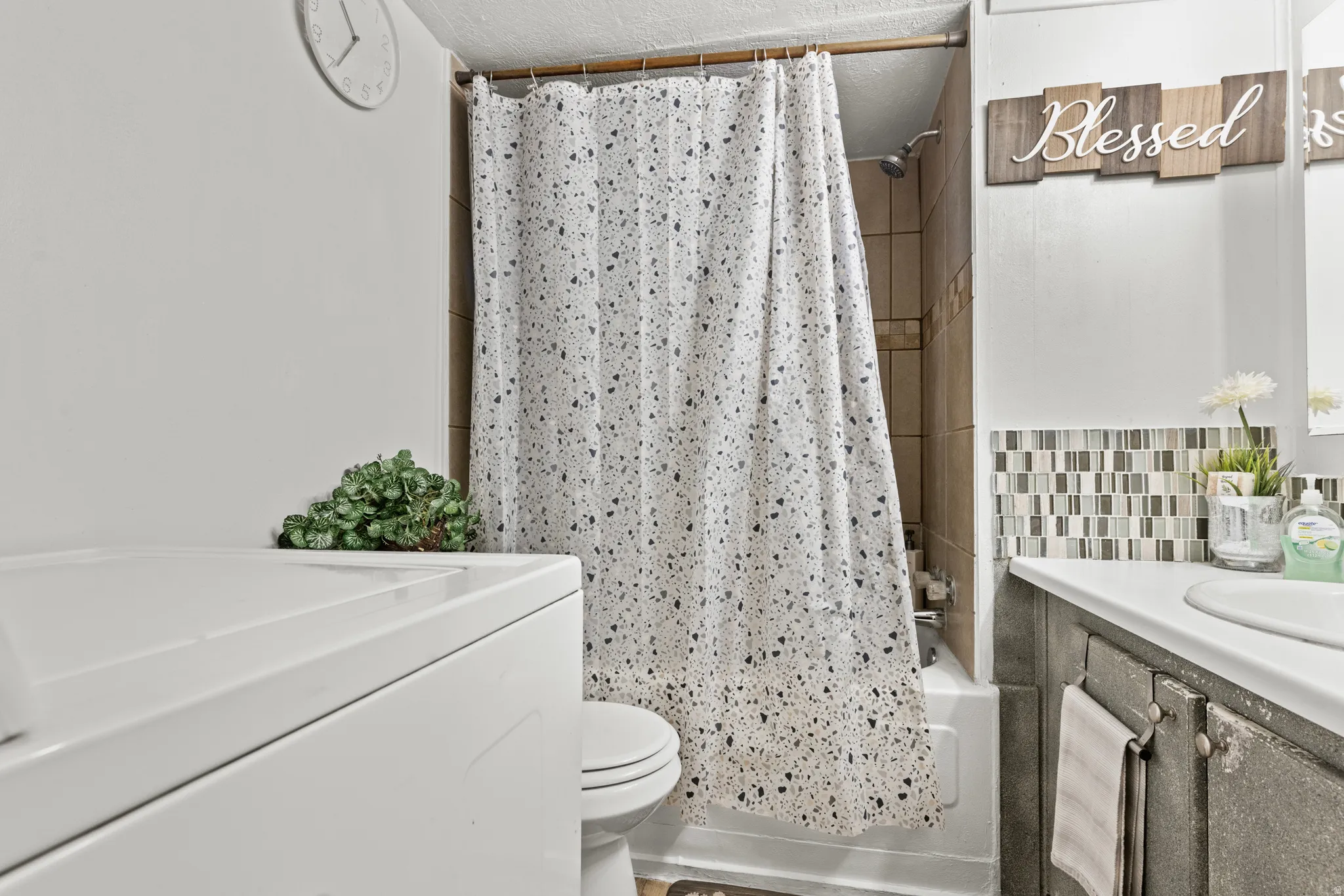 Full bathroom featuring a shower-tub combination with natural stone tile surround, a white porcelain toilet, and a vanity with a white countertop and rectangular undermount sink