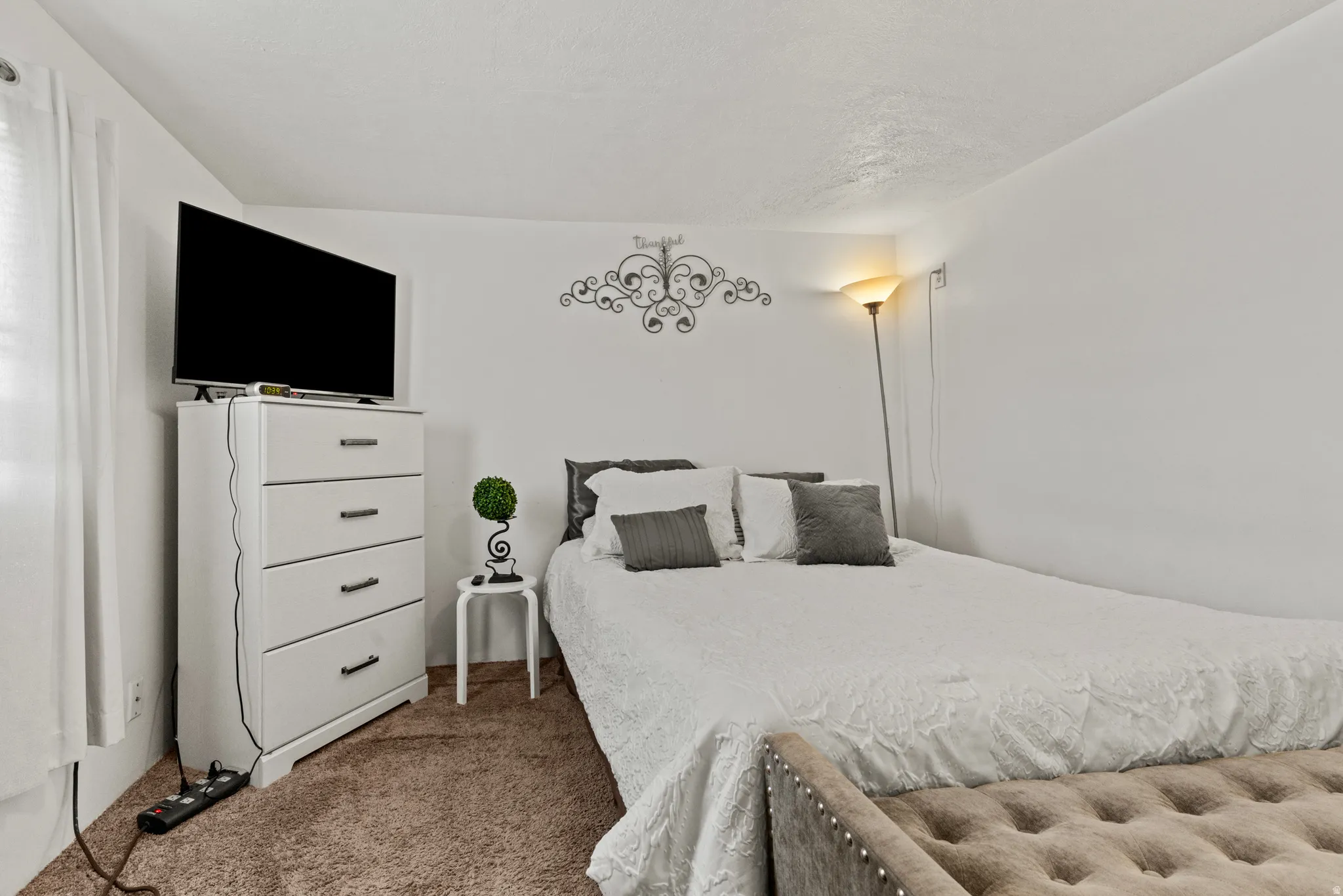 Carpeted room with a white textured ceiling and light-colored walls