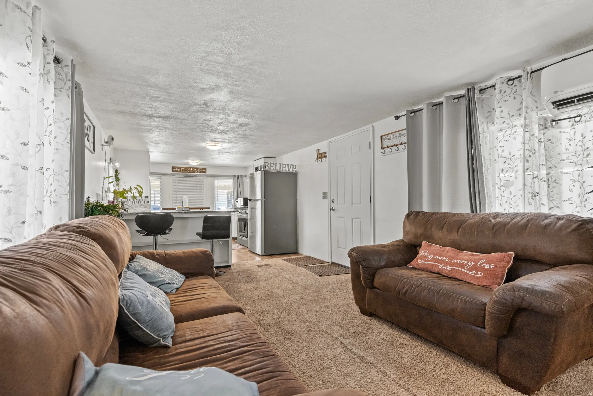 Open-concept living space featuring textured ceilings and neutral carpeting