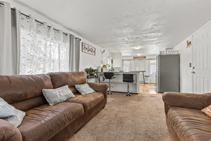 Open concept living space featuring neutral carpet flooring and white walls