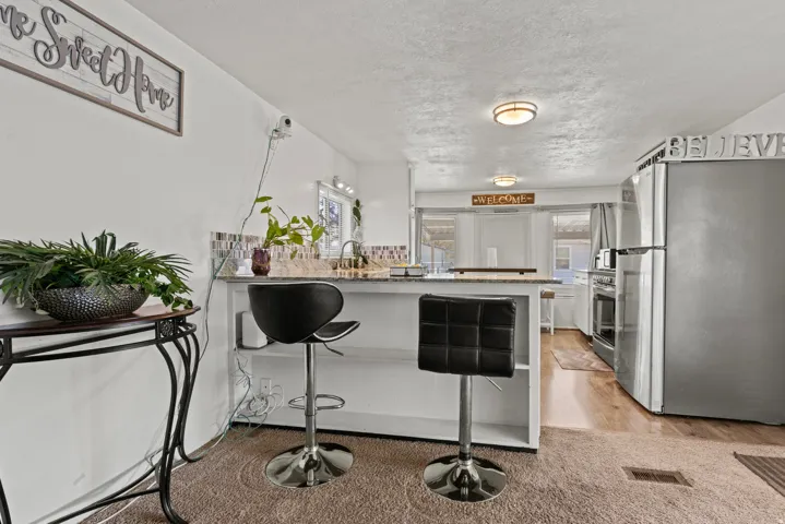 Kitchen featuring a breakfast bar with seating for two, stainless steel refrigerator, and wood-finish flooring
