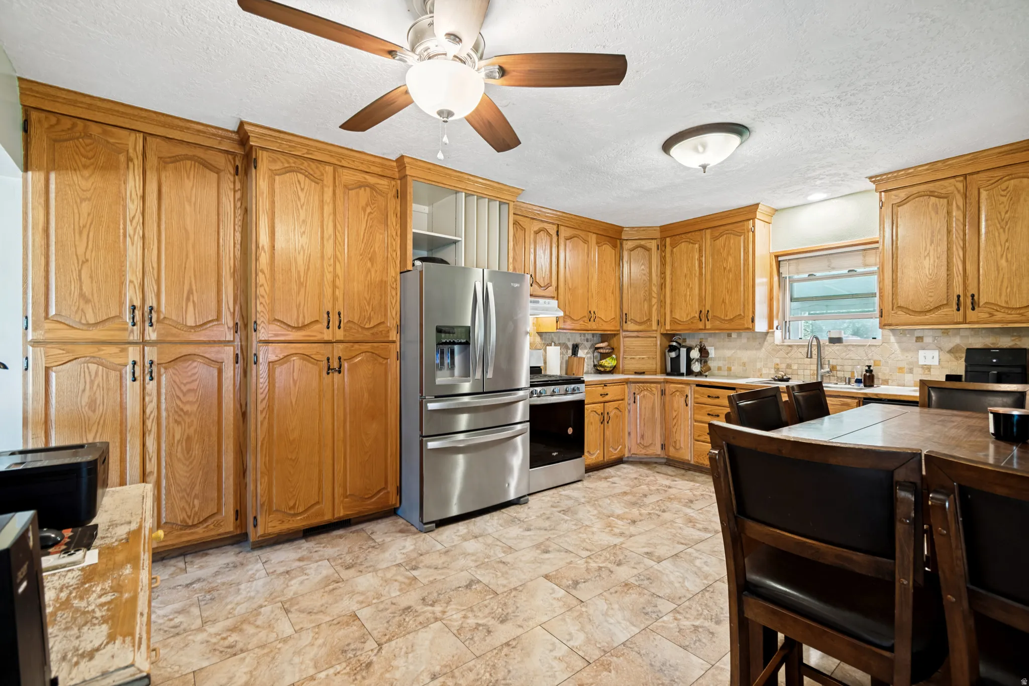 Spacious kitchen featuring extensive wood cabinetry, stainless steel appliances, and a tiled backsplash