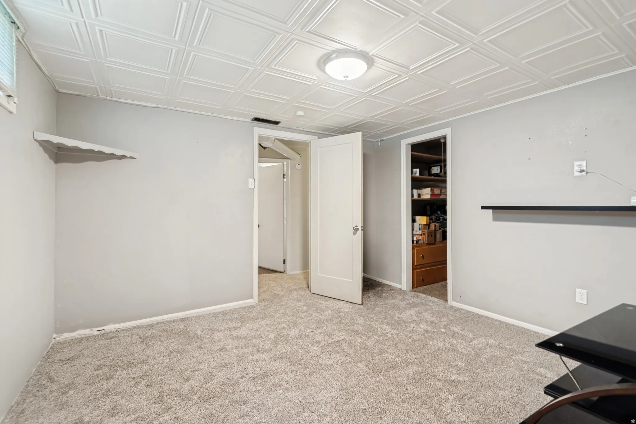 Bedroom featuring light gray walls, new carpet, a patterned ceiling, and a built-in shelf