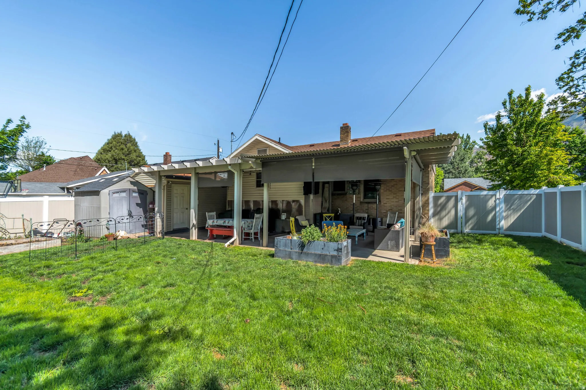 Expansive lawn area featuring a covered patio, a storage shed, and perimeter fencing