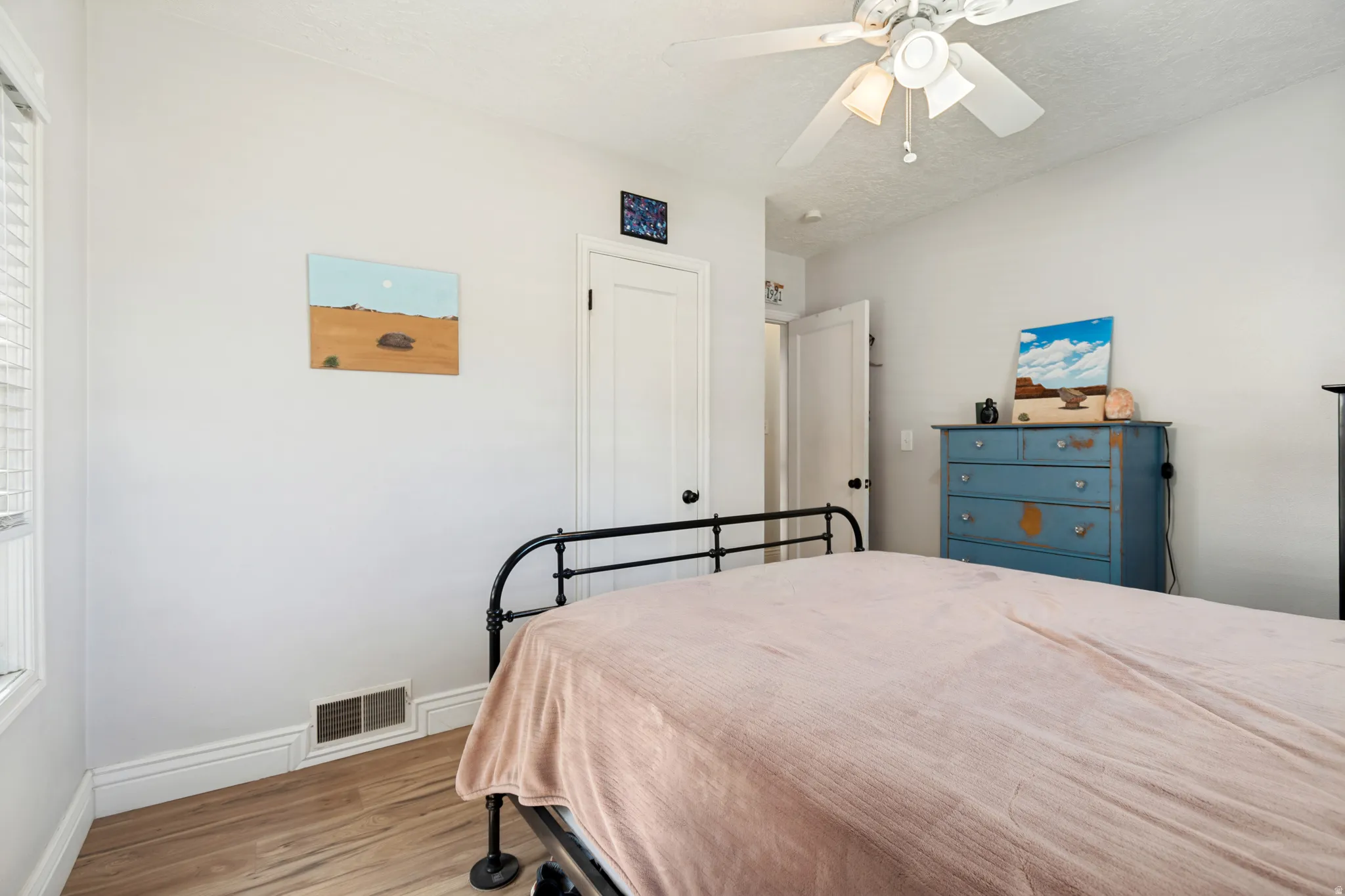 Room featuring wood flooring, white walls, and a ceiling fan with integrated lighting