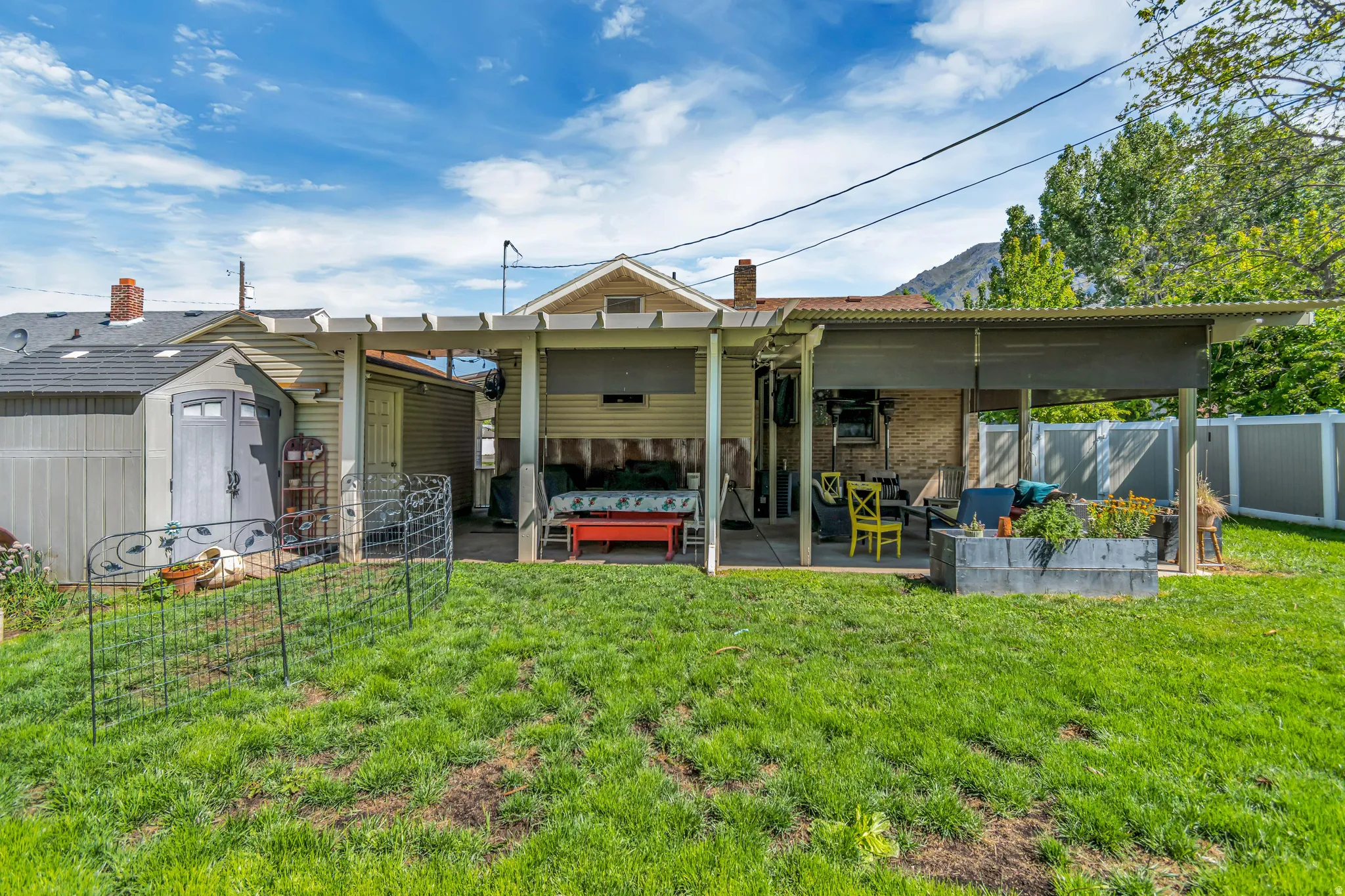 Expansive backyard featuring a covered patio, a separate storage shed, a pergola-style structure, and a wood-slat privacy fence