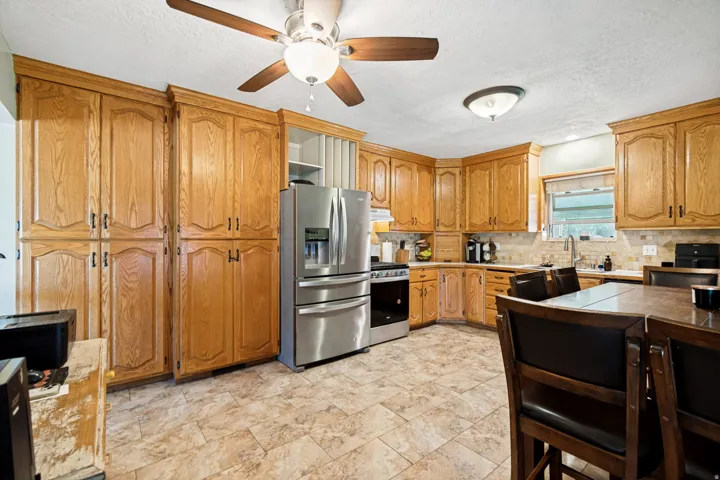 Spacious kitchen featuring extensive wood cabinetry, stainless steel appliances, and a tiled backsplash