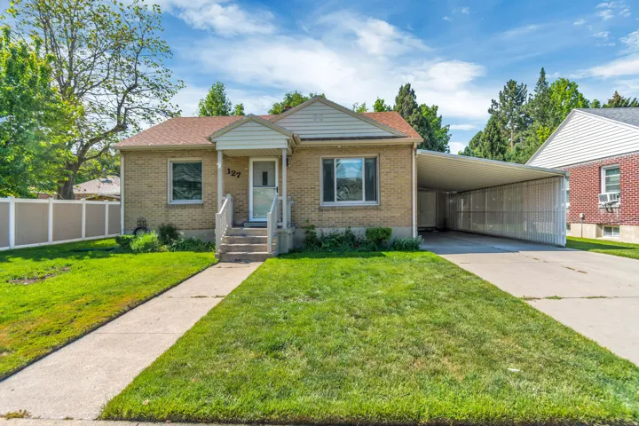 Brick exterior residence featuring a covered front porch, concrete walkway, and a spacious carport
