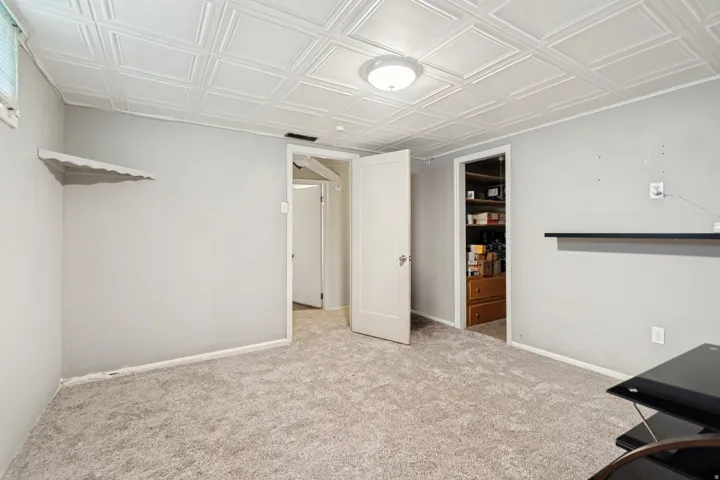 Bedroom featuring light gray walls, new carpet, a patterned ceiling, and a built-in shelf
