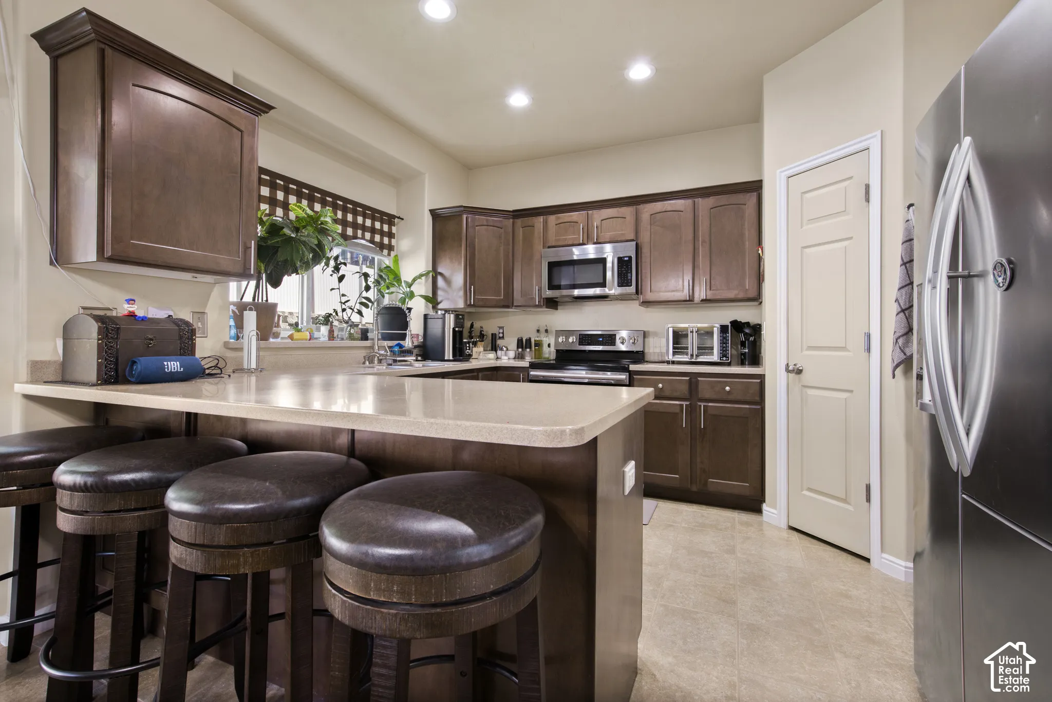 Kitchen featuring wood-finish cabinetry, stainless steel appliances, light-toned countertops, and recessed lighting