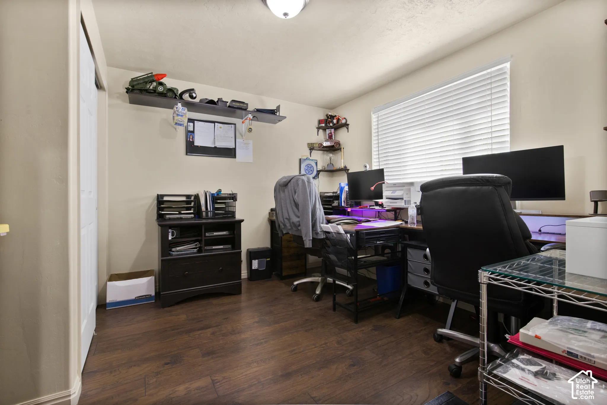 Room featuring wood-finish flooring, a double window with blinds, and light-colored walls