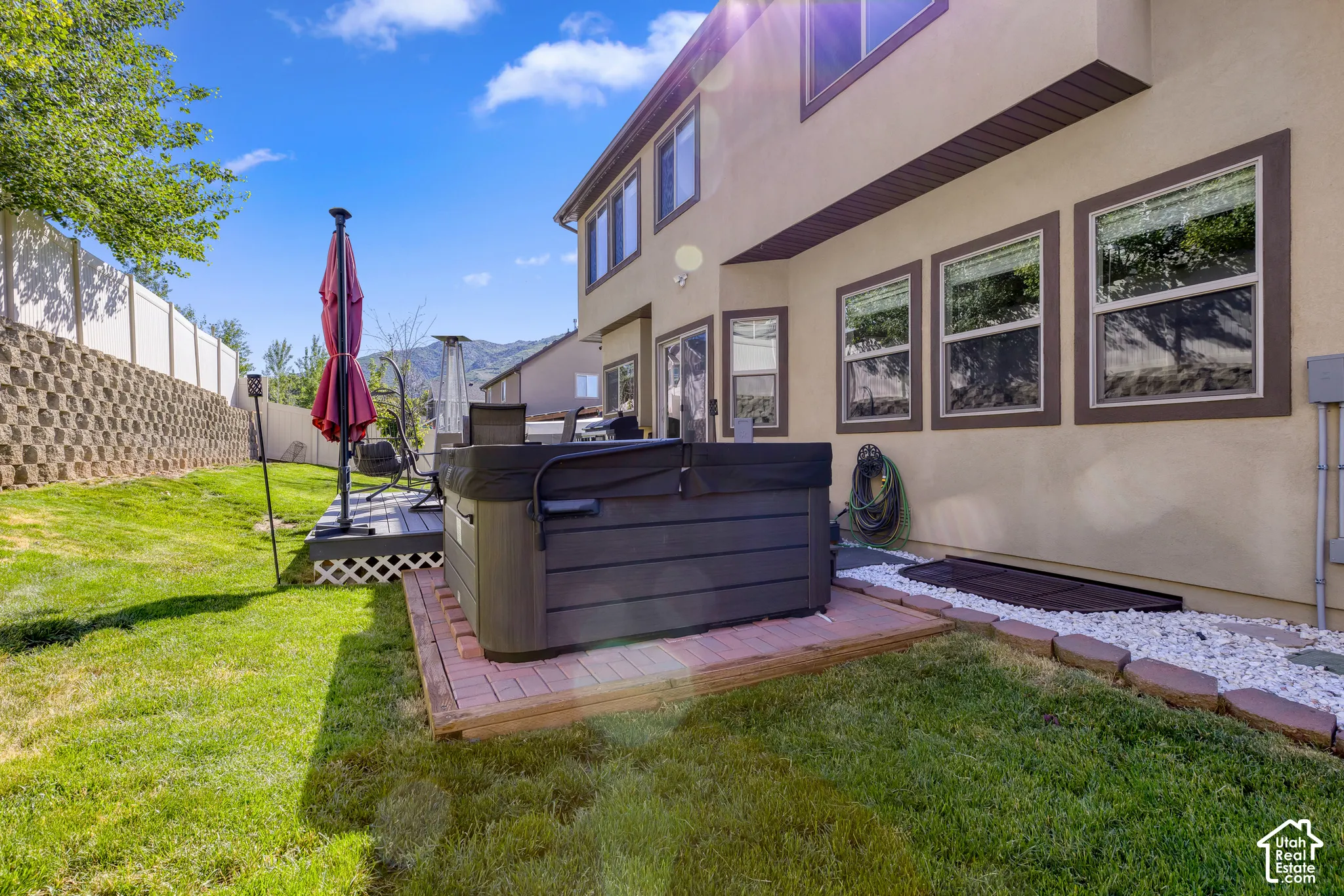 Expansive backyard featuring a built-in hot tub on a brick paver base, a multi-level deck with lattice skirting, and a manicured lawn