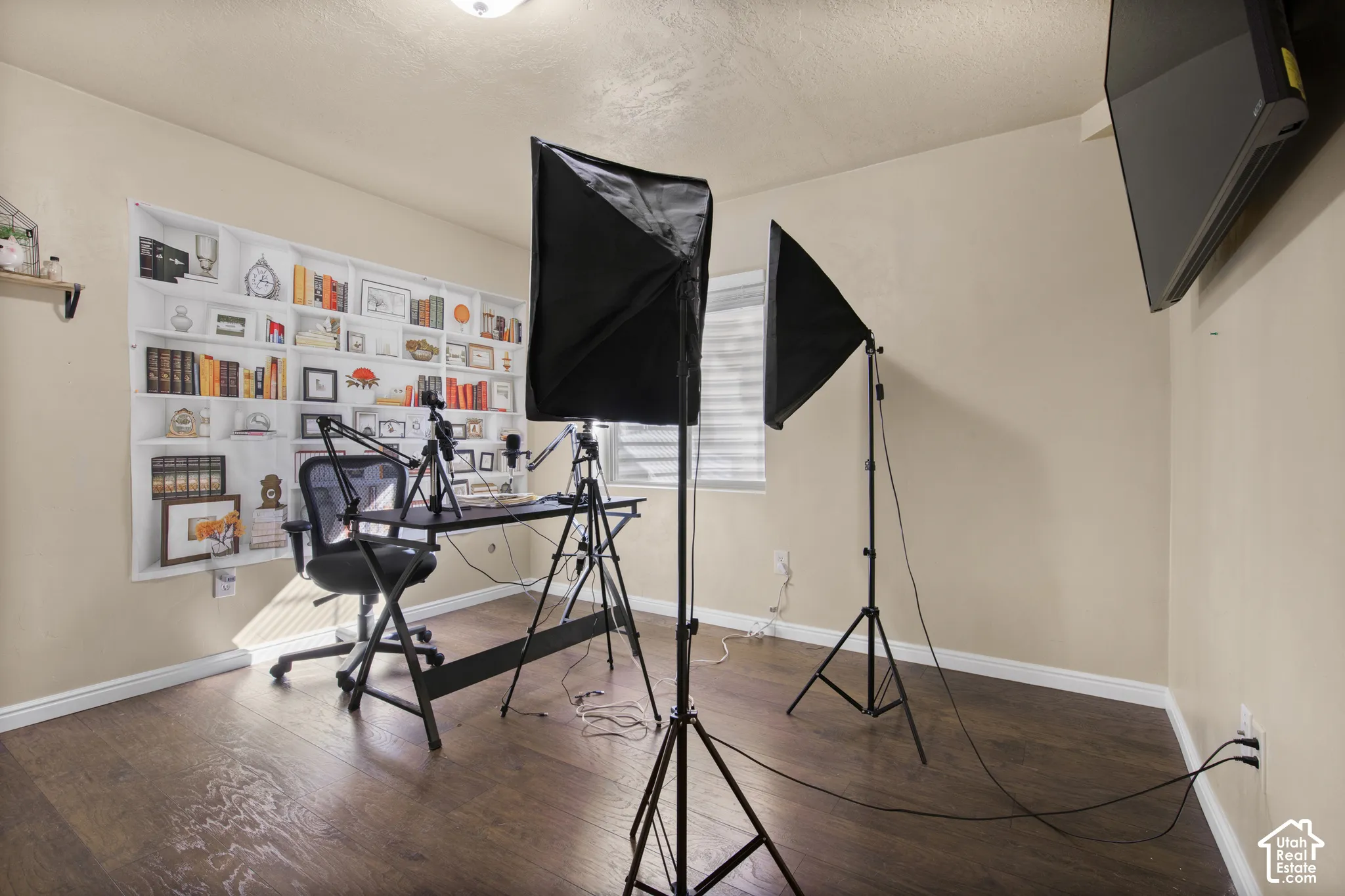 Room featuring wood-finish flooring, neutral wall paint, white baseboards, and a single window with horizontal blinds