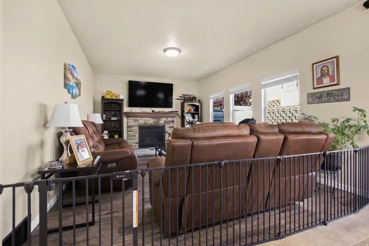 Living area featuring wood-finish flooring, a stone-faced fireplace, and a vaulted ceiling