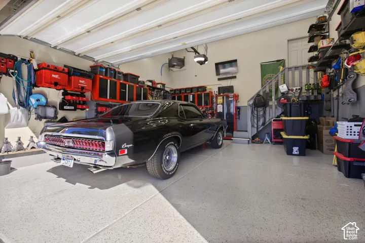 Spacious garage featuring a durable epoxy floor, built-in wall shelving, and overhead sectional doors