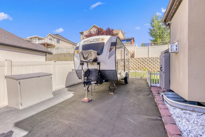 Paved side yard with privacy fencing, retaining wall, and built-in exterior storage unit