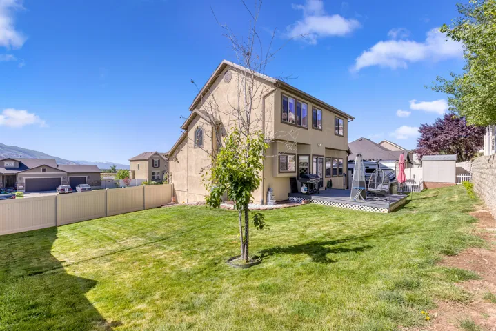Spacious backyard featuring a multi-level deck, manicured lawn, and a vinyl privacy fence