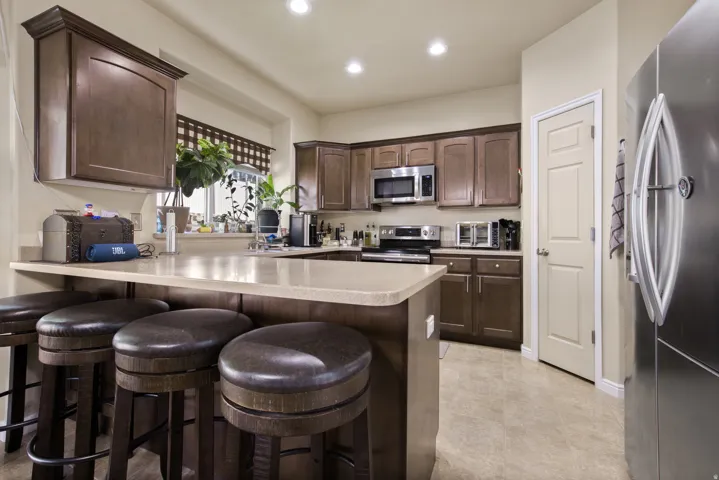 Kitchen featuring wood-finish cabinetry, stainless steel appliances, light-toned countertops, and recessed lighting