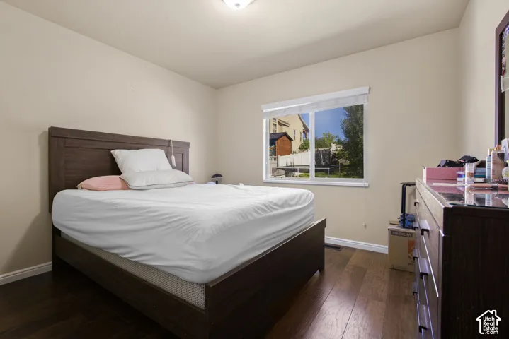 Bedroom featuring wood-finish flooring, a window with exterior views, and a ceiling light fixture