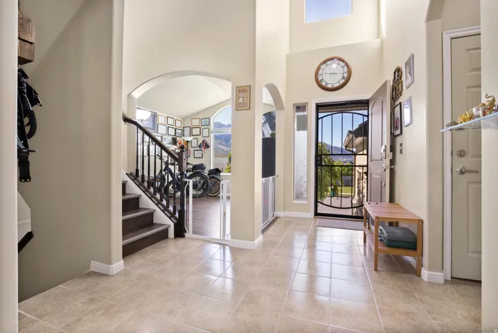 Two-story entryway featuring tile flooring, vaulted ceilings, and a front entry door with an iron security gate