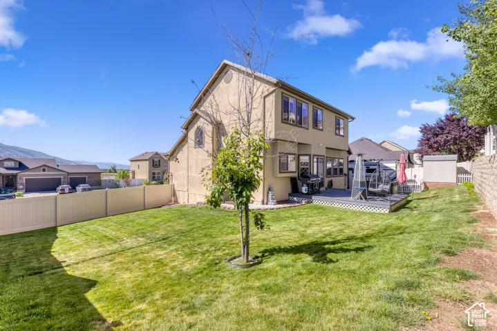 Spacious backyard featuring a multi-level deck, manicured lawn, and a vinyl privacy fence
