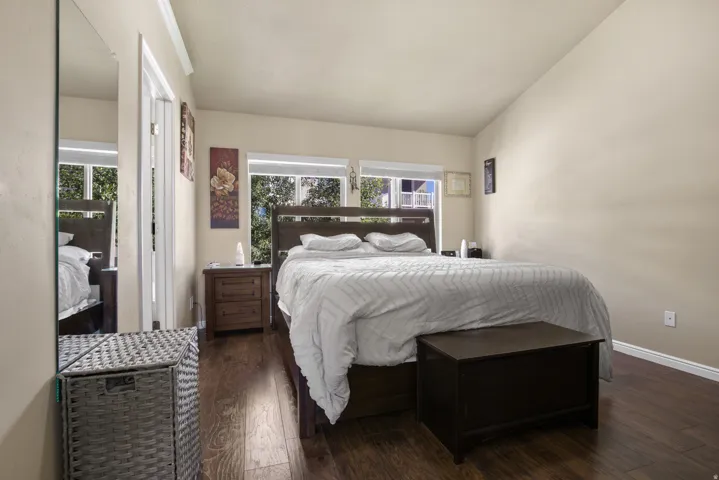 Vaulted ceiling bedroom featuring wood-finish flooring