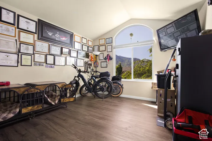 Arched window with mountain scenery and natural light, complemented by wood-finish flooring and vaulted ceilings