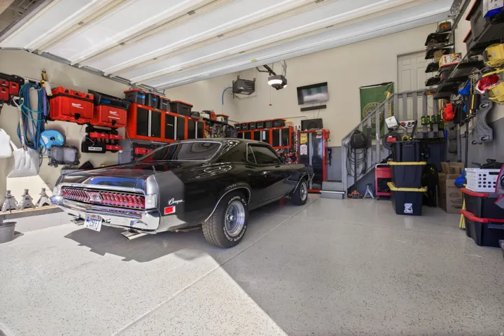 Spacious garage featuring a durable epoxy floor, built-in wall shelving, and overhead sectional doors